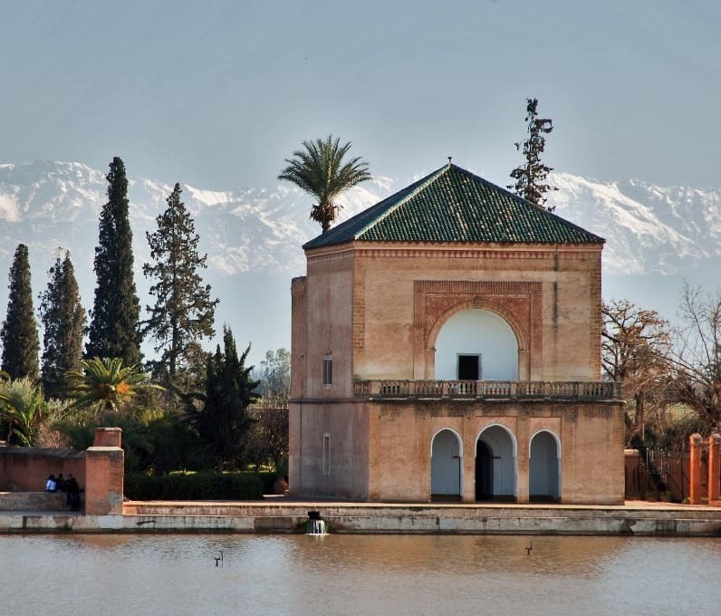 vista de los jardines menara de marrakech antes de las montañas nevadas